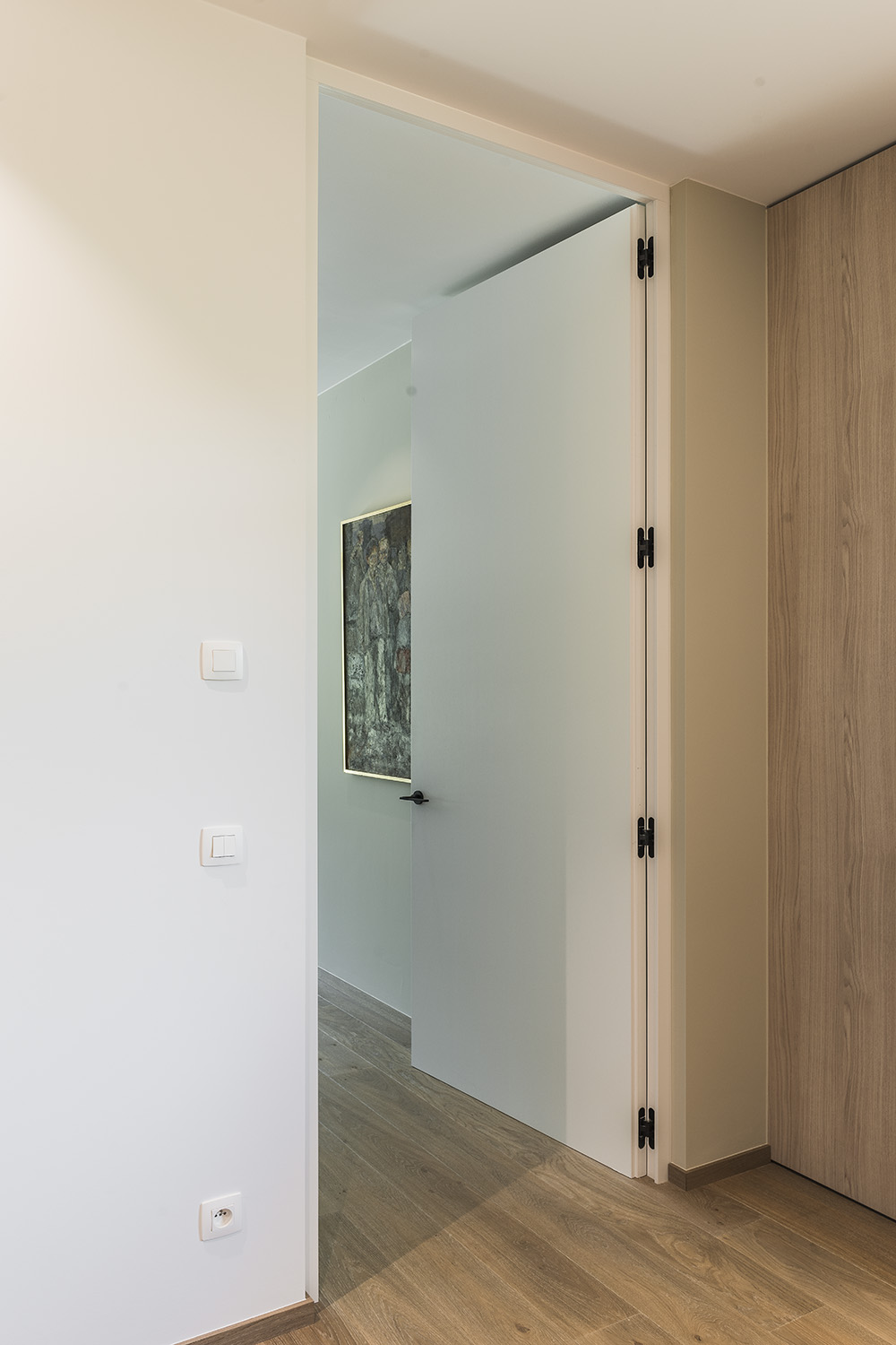Integratie van onzichtbare scharnieren voor houten deuren die vlak liggen met de wand.
